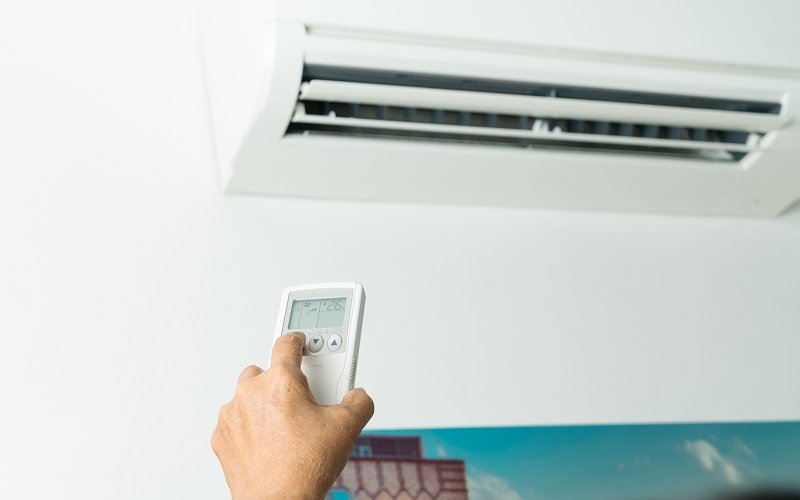 Person using remote control to operate noisy aircon unit.